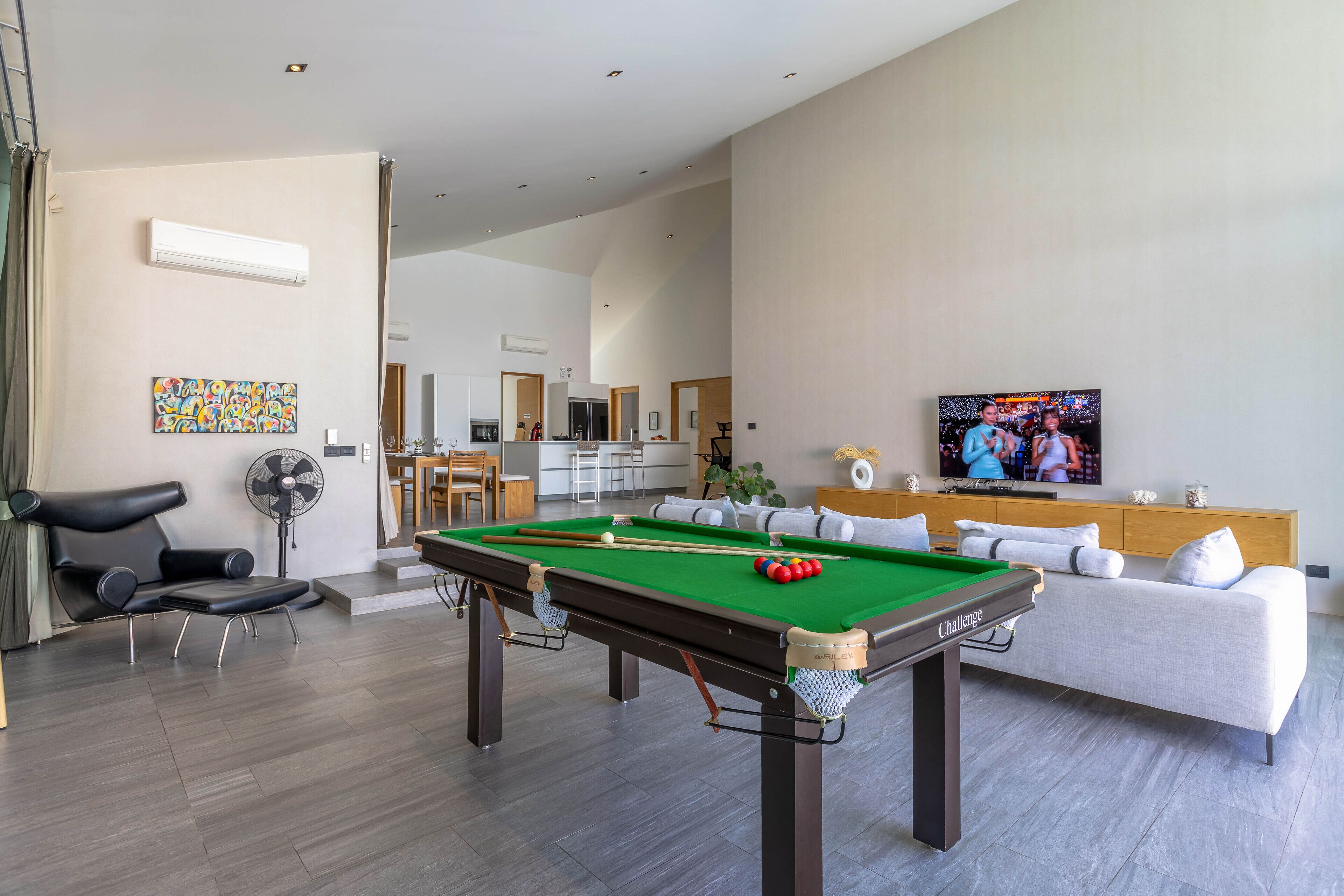 A modern living room with a pool table, a sofa, and a television.