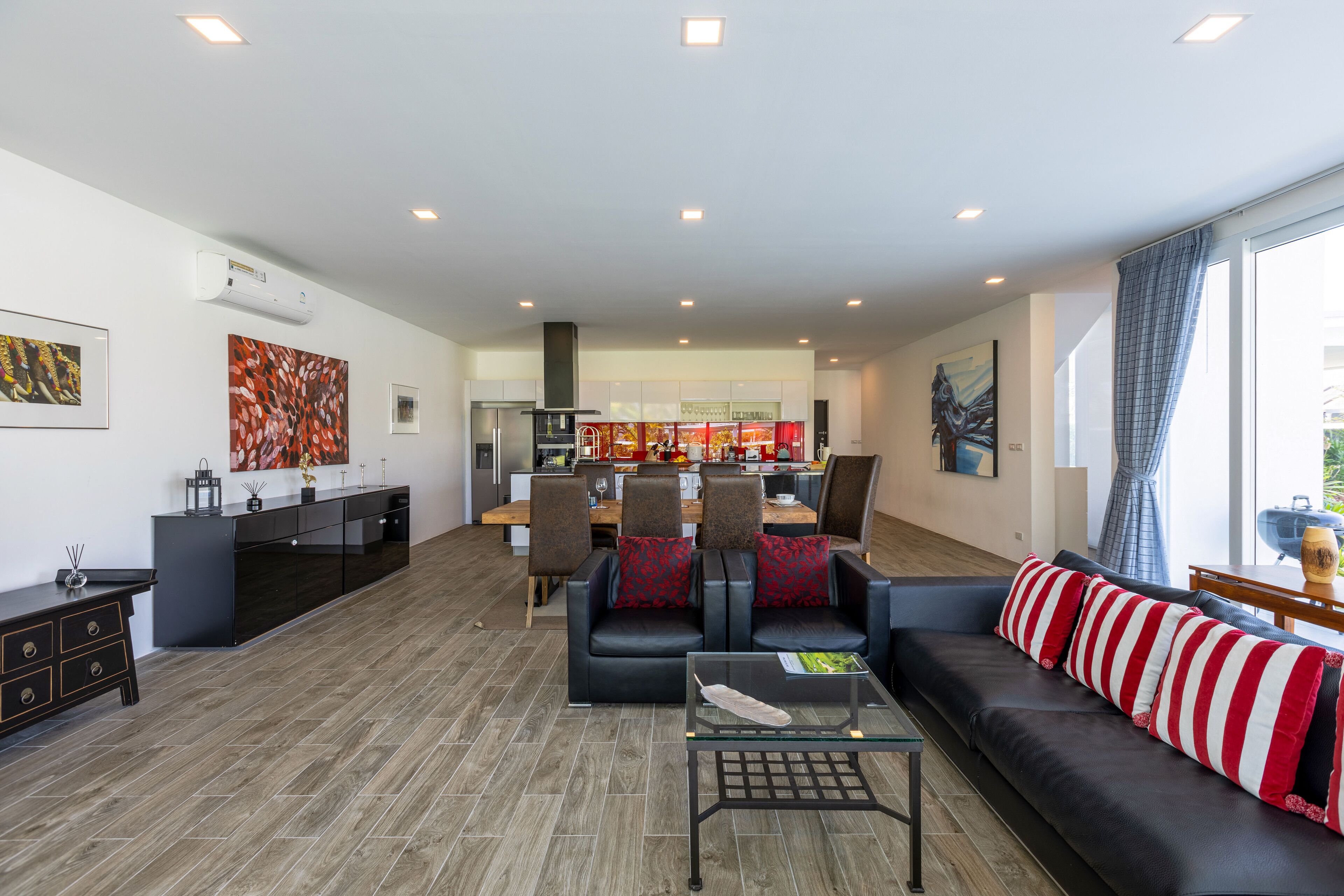 A modern living room with a sofa, coffee table, and a dining area in the background.