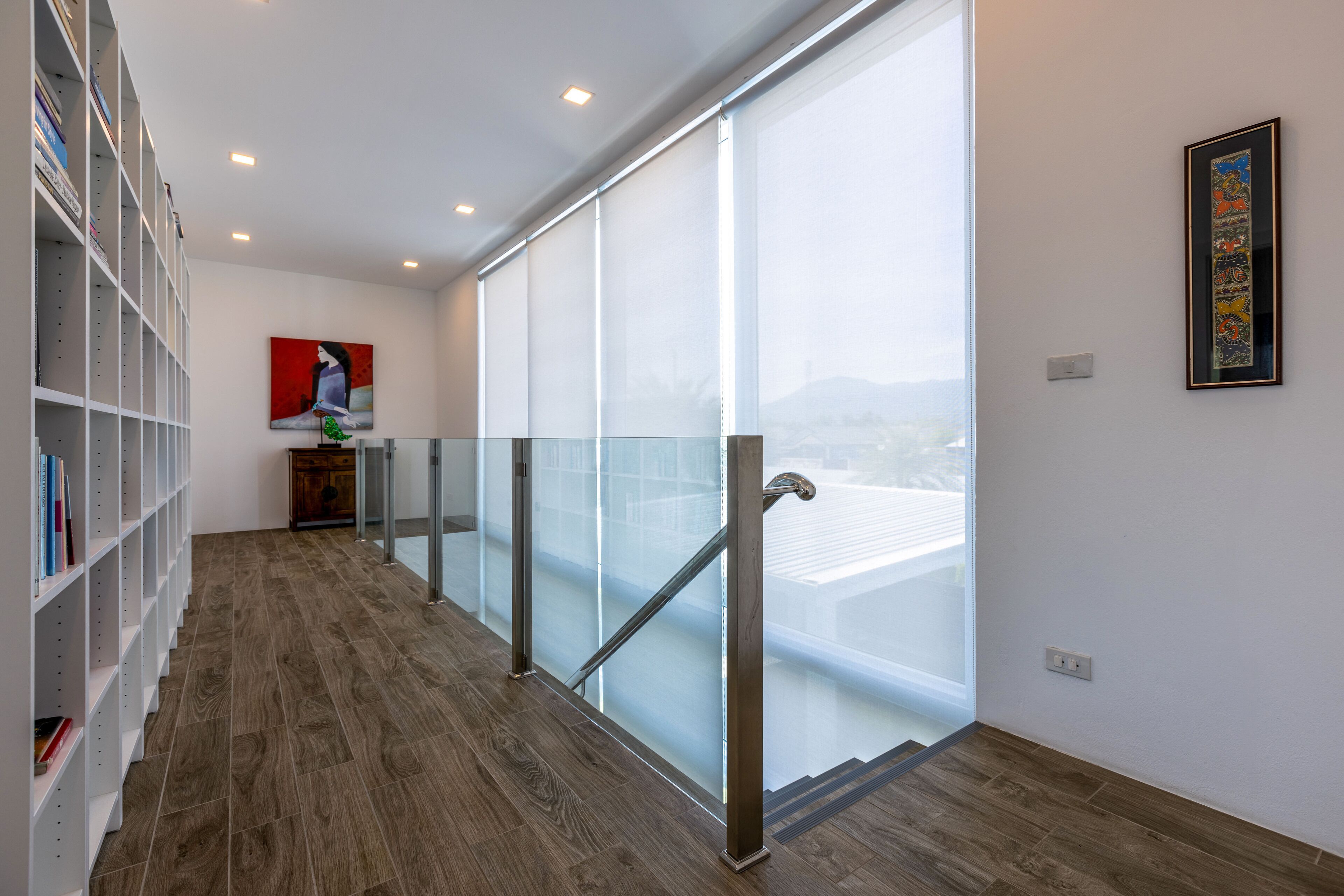 A modern interior with a wooden floor, a glass railing, and a city view.