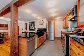 Kitchen features a central island with sink, stove, and refrigerator, plus a range hood and clock.