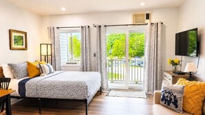 Une chambre à coucher avec un lit, un canapé, une télévision et un balcon avec des rideaux.