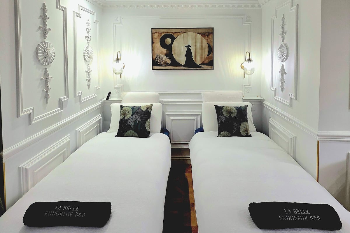 Une chambre d’hôtel avec deux lits, un plafond décoratif et un tableau au mur.