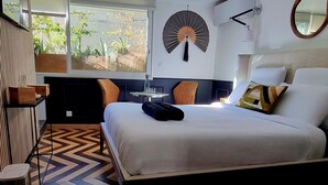 A modern bedroom with a large bed, a round wall hanging, a ceiling fan, and a window with a view of greenery. - La Belle Endormie B&B (Bordeaux)