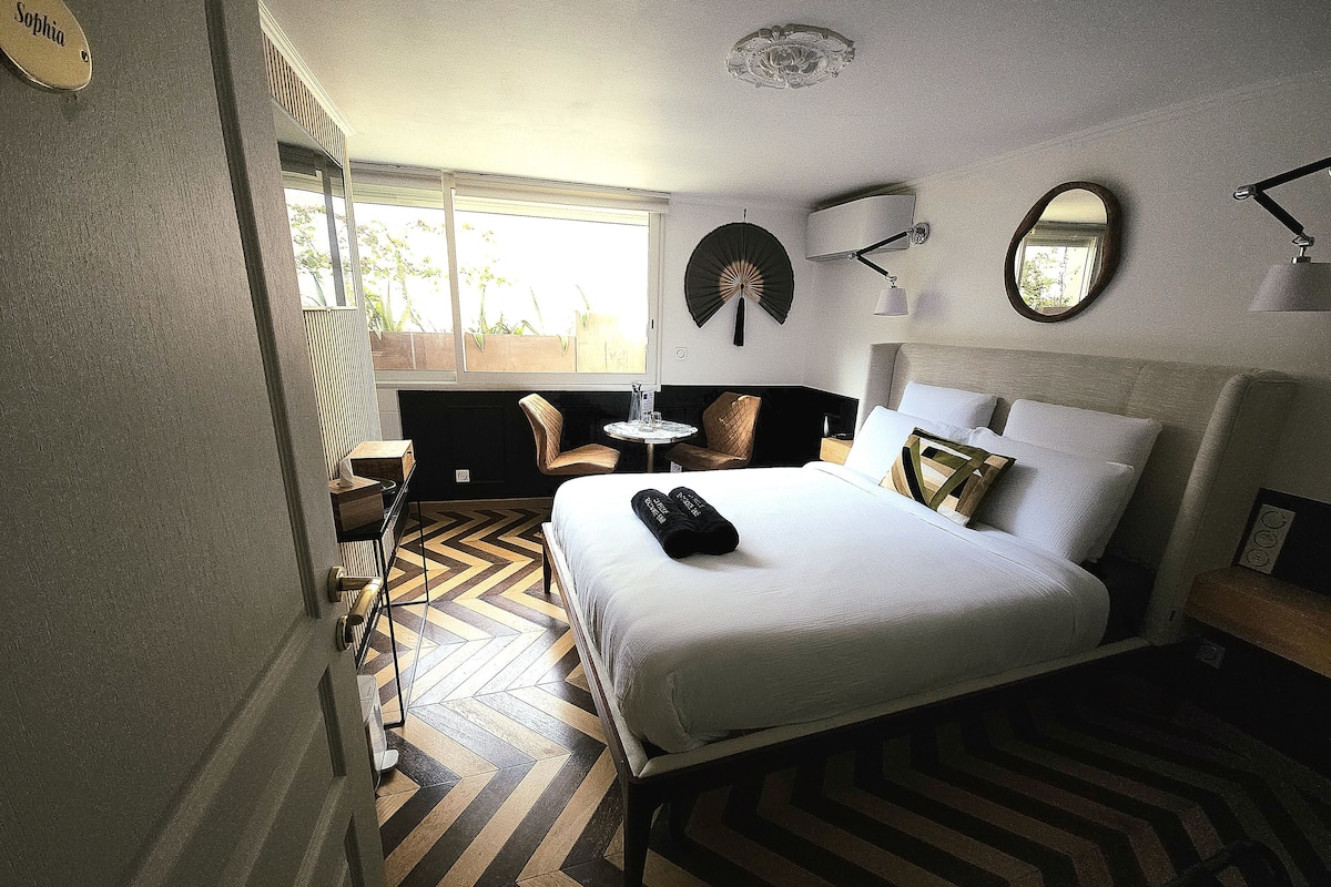 Une chambre d’hôtel avec un lit, une chaise, une petite table et une fenêtre.