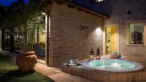 A brick house with a hot tub and a wooden deck. - Splendid Villa Monte Quercione (Emilia-Romagna)