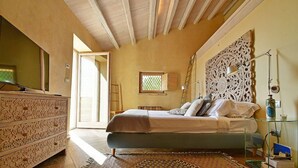 Quarto com cama, penteadeira, janela e um painel decorativo na parede.