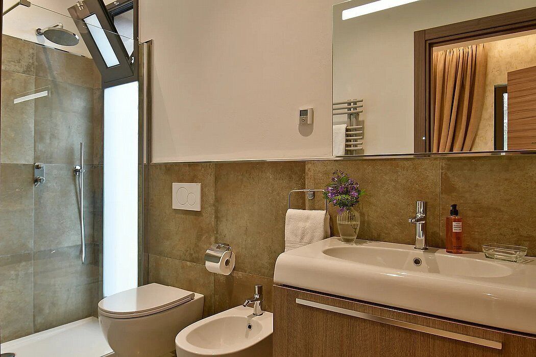 Une salle de bain moderne équipée d’une douche, de toilettes, d’un bidet et d’un grand miroir au-dessus du lavabo.