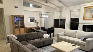 A modern living room with a sectional sofa, a coffee table, a dining area with a table and chairs, and a fireplace. - RENT NOW!! 1st Time NEW Rental Grayhawk Luxury Home Near TPC Scottsdale Shopping (Scottsdale)