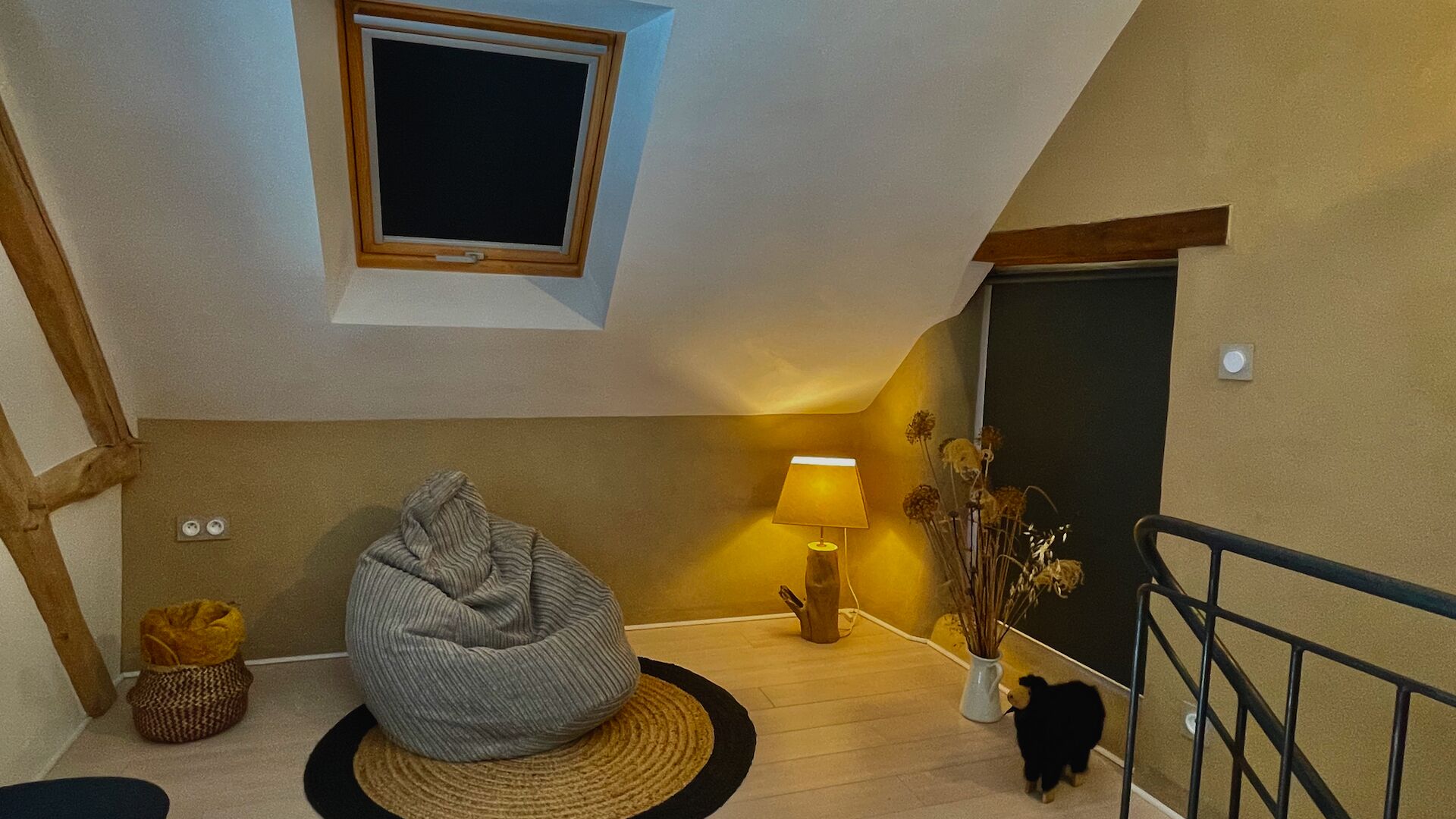 A cozy room with a bean bag chair, a lamp, and a vase with dried flowers.