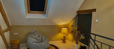 A cozy room with a bean bag chair, a lamp, and a vase with dried flowers.