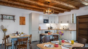Una cocina moderna con armarios blancos, una mesa de comedor de madera y una lámpara colgante.