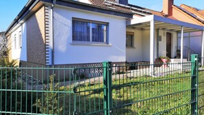 A two-story house with a white exterior, a visible window, and a green metal fence in the foreground. - Convenient (Bad Vilbel)