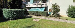 A residential building with a green awning, a pathway, and well-maintained hedges.