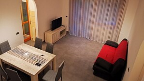 Un salon avec un téléviseur, une table à manger et un canapé.