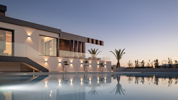 Un bâtiment moderne doté d’une piscine, caractérisé par un design épuré et un éclairage extérieur.