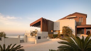 Une maison moderne à plusieurs étages, dotée d’un toit plat, de grandes fenêtres et d’un balcon.
