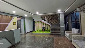 Un vestíbulo con una escalera, un mostrador de recepción y una zona de estar.