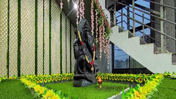 Una estatua de una deidad en un jardín con una cerca ornamentada y girasoles.