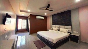 Un dormitorio moderno con una cama grande, ventilador de techo, unidad de aire acondicionado, televisor de pantalla plana y una pared de acento de mármol.