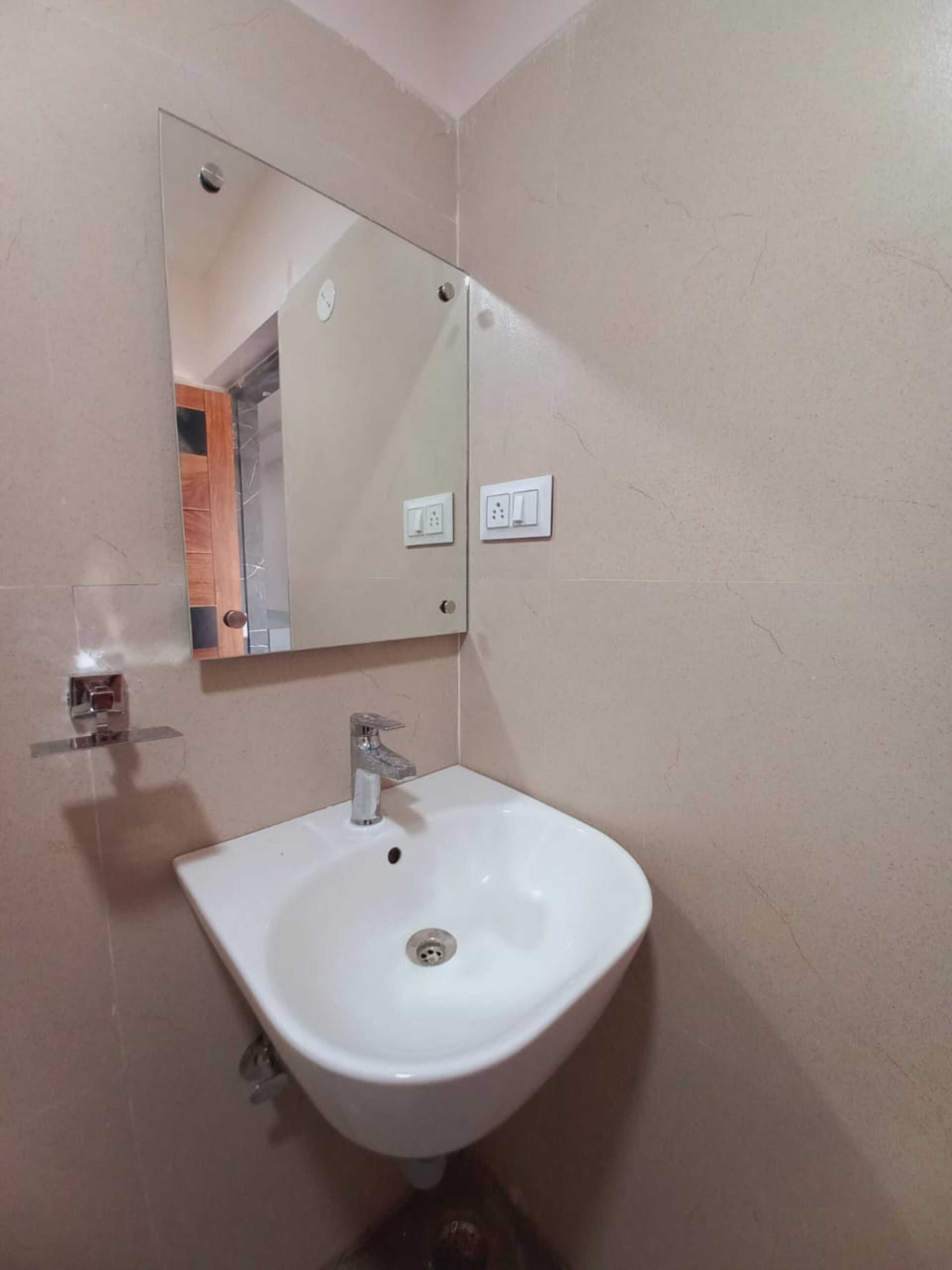 Ein Badezimmer mit einem weißen Waschbecken, einem Spiegel und zwei Steckdosen an der Wand.