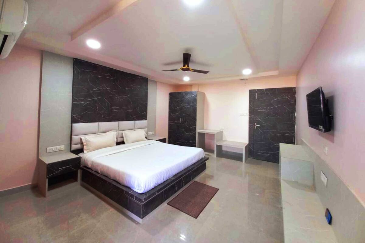 A modern bedroom with a bed, nightstands, a TV, and a ceiling fan.
