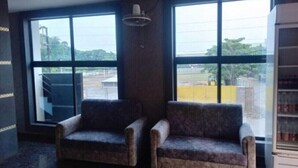 Una habitación con dos sillones, ventanas amplias y un ventilador de techo.