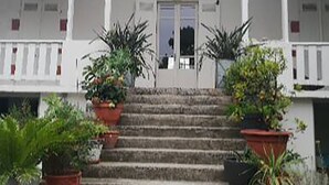En bygning med en symmetrisk facade, en midterindgang med dør, og en overdækket veranda med plantekasser.