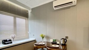 A compact kitchen with a dining area, featuring a built-in stove, a window with blinds, and a herringbone-patterned floor. - Fan's Hotel Ormoc (Ormoc)