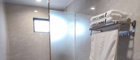 A modern bathroom with a toilet, shower, and towel rack.