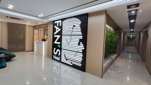 A hotel reception area with a modern design, including a reception desk, a seating area, and a hallway with a plant and a sign for the FANS Hotel. - Fan's Hotel Ormoc (Ormoc)