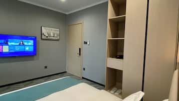 Et hotelværelse med en seng, et fjernsyn ophængt på væggen og et klædeskab.
