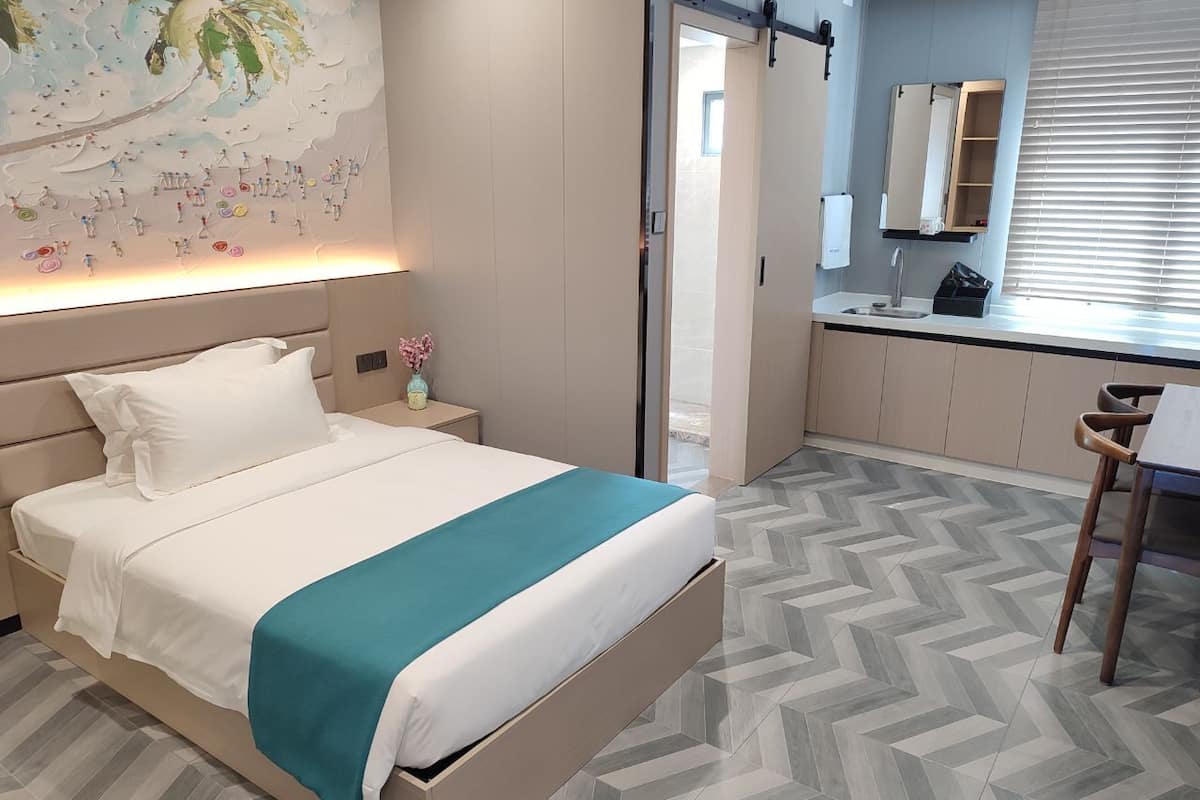 Una habitación de hotel moderna con cama, mesita de noche y escritorio con silla.