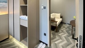 A hotel room with a built-in wardrobe, a bed with a white headboard, and a small table with a vase. - Fan's Hotel Ormoc (Ormoc)