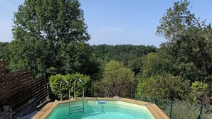 Une piscine rectangulaire à l’eau claire, entourée d’une terrasse en bois et de rampes métalliques.