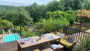 Une terrasse en bois avec une piscine, une table avec des coussins et un banc.