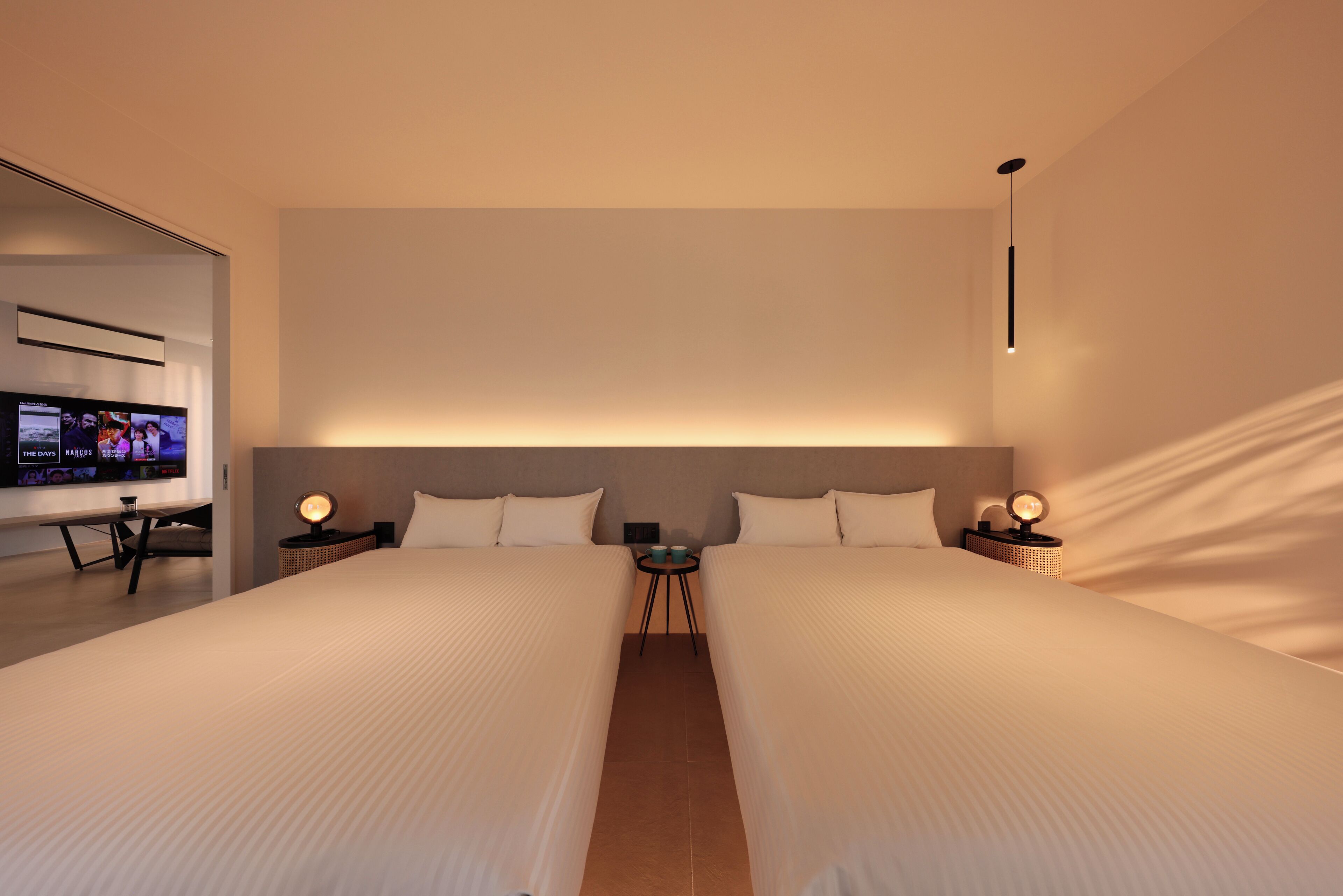 Een moderne hotelkamer met twee bedden, een flatscreen televisie en sfeerverlichting.