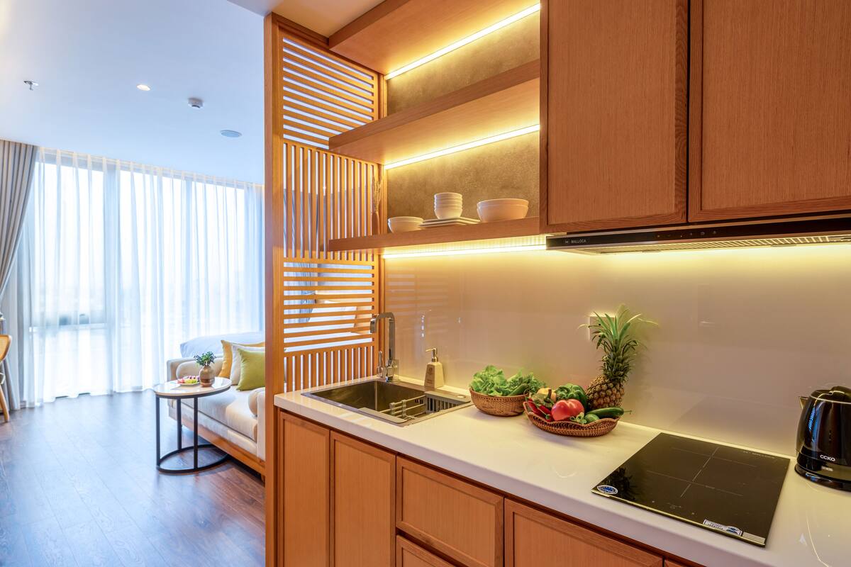 A modern kitchen with wooden cabinets, a built-in oven, and a countertop with a kettle.