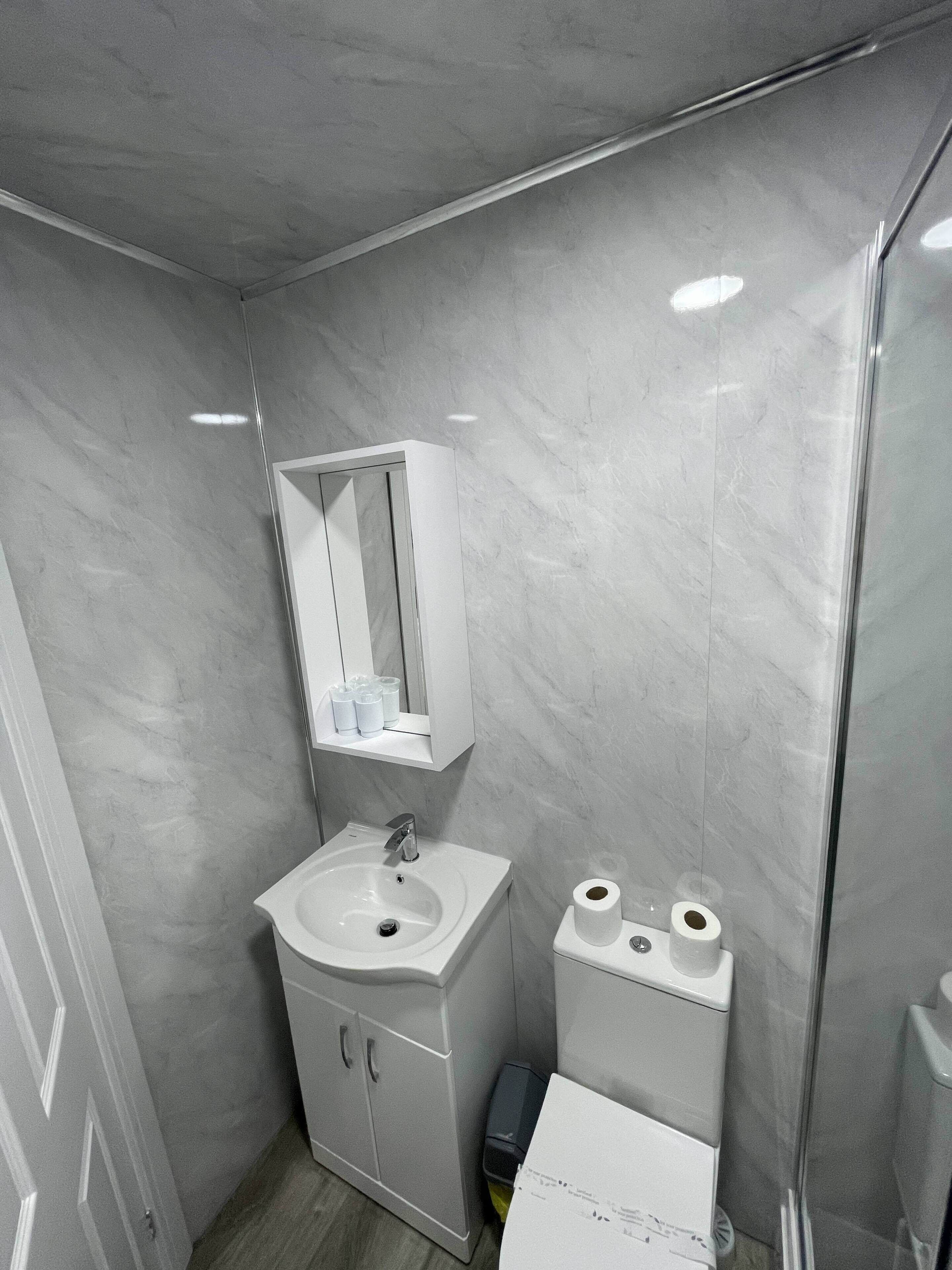 A bathroom with a white sink, mirror, and toilet.