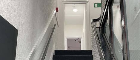 A staircase with a handrail, carpeted steps, and a wall with a textured pattern.