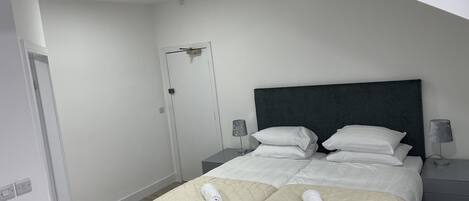 A modern bedroom with a large bed, two bedside tables, and a door.