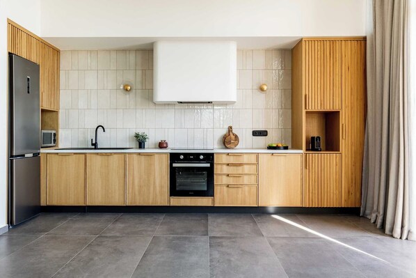A modern kitchen with wooden cabinets, a built-in oven, and a stainless steel refrigerator. - Beach Villa In Crete - Villa Alope (Ierapetra)