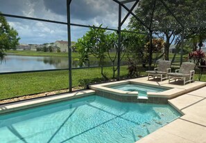 A swimming pool with a view of a lake, surrounded by a covered area with chairs and plants.