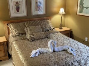 A bedroom with a bed, pillows, a bedside lamp, and artwork on the walls.