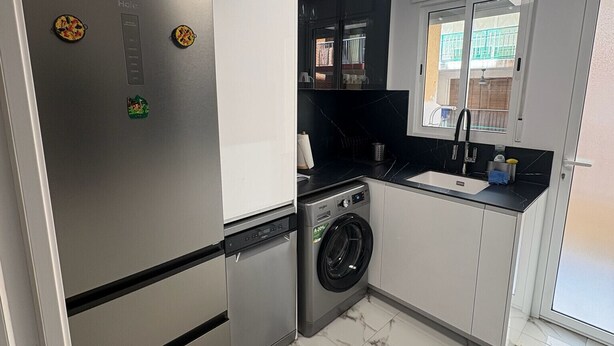 A compact kitchen with a built-in washing machine, a refrigerator, and a window with a view of the outside. - BELGICA, ESC-2, 4º-8 (Cullera)