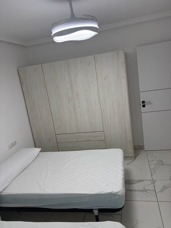 A bedroom with a bed, a wardrobe, and a ceiling light fixture.
