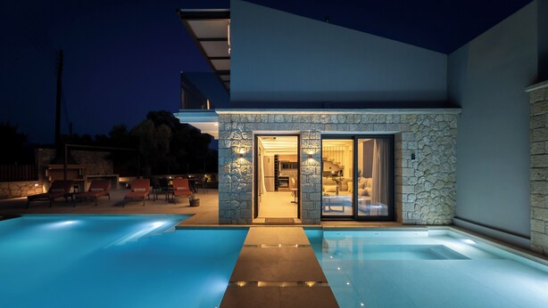 Una casa moderna con piscina, fachada de piedra y puertas de vidrio que dan a una sala de estar.