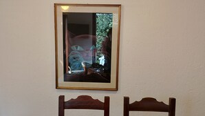 A dining table with a wooden tray holding bowls, two chairs, and a framed picture on the wall. - Holiday House Camillina (Salò)