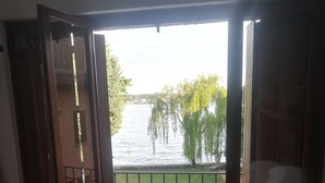 A balcony with wicker chairs and a view of a lake with trees. - Holiday House Camillina (Salò)