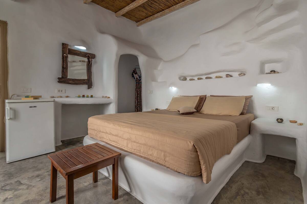 A bedroom with a bed, bedside table, and a small wooden table.