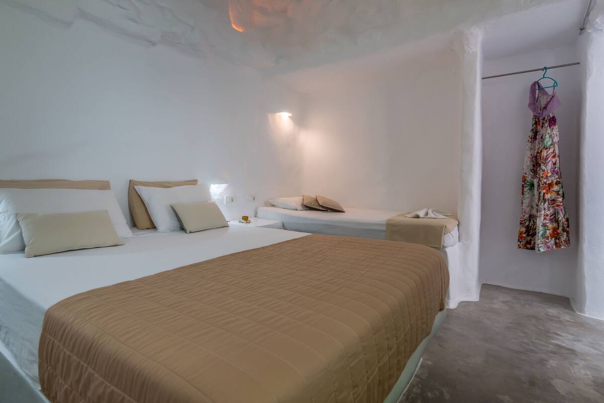 A hotel room with a large bed, a smaller bed, and a nightstand with a lamp.